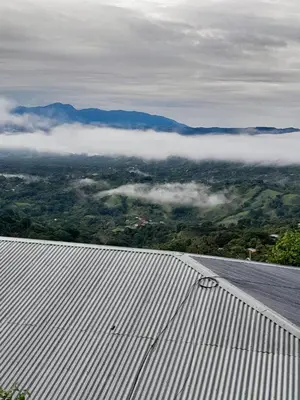 a view from the roof of a building of a valley with clouds at Hospedaje Coffee Mountain in San Isidro