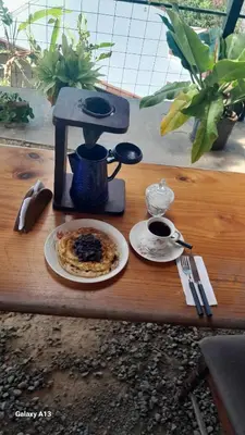 a table with a coffee maker and a plate of food at Hospedaje Coffee Mountain in San Isidro