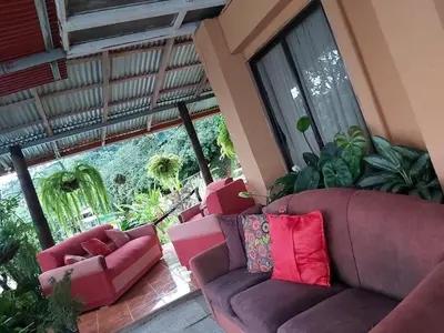 a living room with two couches and a large window at Hospedaje Coffee Mountain in San Isidro