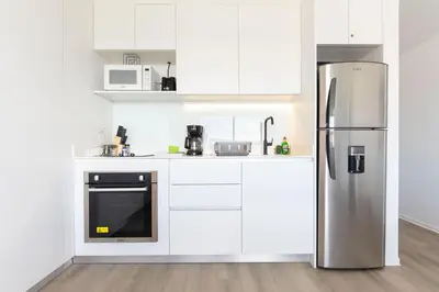 a kitchen with white cabinets and a stainless steel refrigerator at Brand new 1 bed loft with spectacular city view in El Empalme