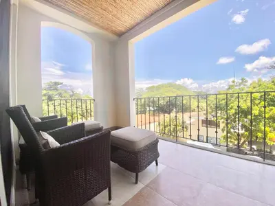 a room with a balcony with chairs and a large window at Peninsula 46 - Upscale 2bdr with Jacuzzi - Beach - Fast wifi - Gym in Tamarindo