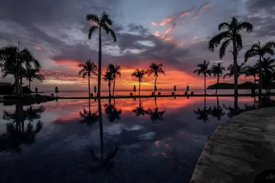 a pool with palm trees and a sunset in the background at Palms 20 Luxury Oceanfront Villa in Playa Flamingo