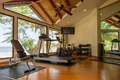 a gym with cardio equipment in a room with windows at Palms 20 Luxury Oceanfront Villa in Playa Flamingo