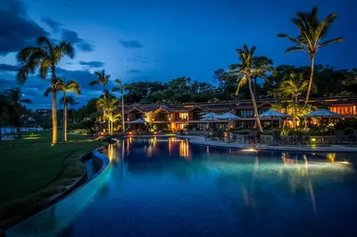 a resort with a swimming pool at night at Palms 20 Luxury Oceanfront Villa in Playa Flamingo