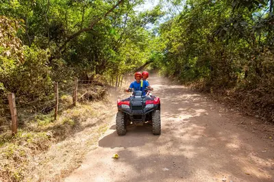 two people riding on a four wheeler on a dirt road at Palms 20 Luxury Oceanfront Villa in Playa Flamingo