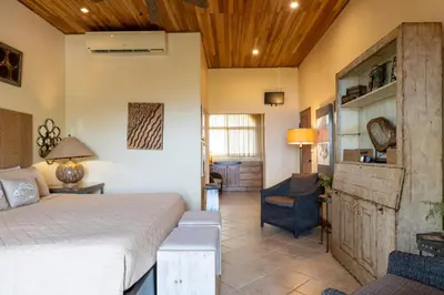 a bedroom with a bed and a chair in a room at Casa Rosa- Luxury Ocean View 3 Bedroom Home in Brasilito