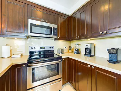 a kitchen with wooden cabinets and stainless steel appliances at 360 Splendor 404-Ocean View Condo- With Breakfast in Playa Flamingo