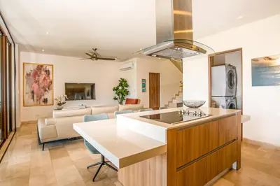 a kitchen and living room with a kitchen island and a couch at Private Pool Townhouse with Partial Ocean View - Aromo - Reserva Conchal in Playa Conchal