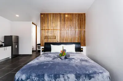 a bedroom with a large bed and a kitchen at House of Nomad - Adults only in Tamarindo
