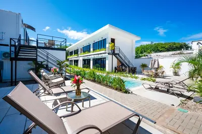 a patio with chairs and a pool and a building at House of Nomad - Adults only in Tamarindo