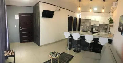a kitchen with a bar with white stools at Casa Bosque GuestHouse & Car Rental - Free SJO Airport Shuttle in Desamparados