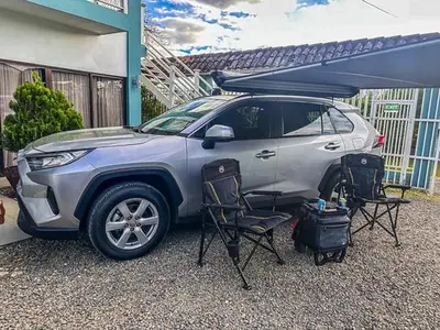 a silver suv parked in a driveway with two chairs at Casa Bosque GuestHouse & Car Rental - Free SJO Airport Shuttle in Desamparados