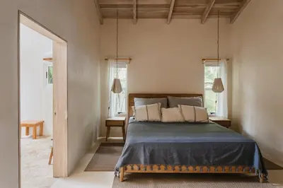 a bedroom with a bed in a room with windows at Casa Arena Beachfront Property in Santa Teresa Beach