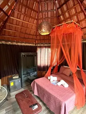 a bedroom with a bed with an orange mosquito net at Casa Tropical Playa Grande in Cuajiniquil