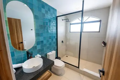 a bathroom with a toilet and a sink and a mirror at Marala Hotel in Esterillos