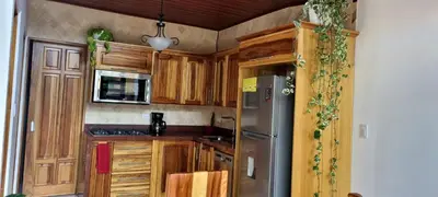 a kitchen with wooden cabinets and a stainless steel refrigerator at La Torre Azul in Alajuela City