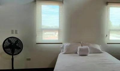 a bedroom with a bed with a fan and windows at La Torre Azul in Alajuela City