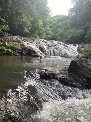a man swimming in a river with a waterfall at Mi casita in Montezuma