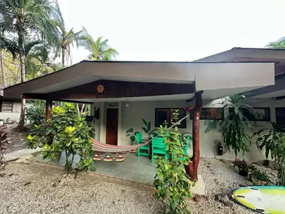 a house with a hammock in front of it at El Sueno Tropical in Carrillo
