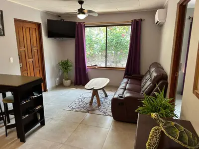 a living room with a leather couch and a window at El Sueno Tropical in Carrillo