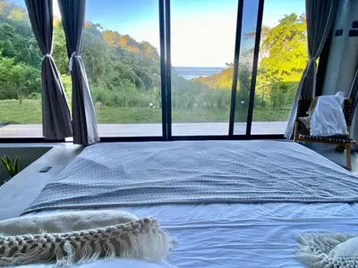 a bed in a room with a large window at CASA BÚHO in Santa Teresa Beach