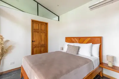 a bedroom with a large bed with a wooden headboard at NAIA OCEANVIEW STUDIO in Carmen