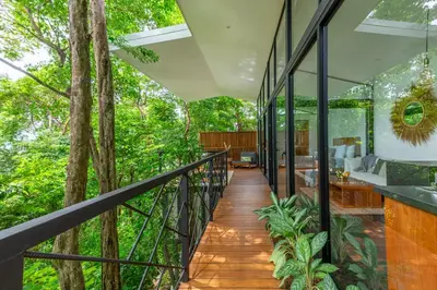 a balcony of a house with glass and trees at NAIA OCEANVIEW STUDIO in Carmen