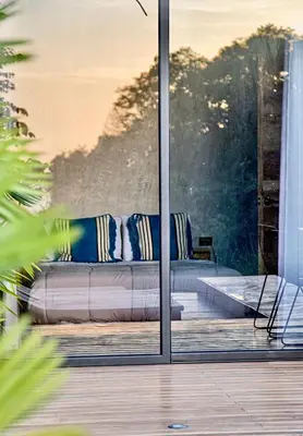 a couch sitting on a porch with a glass door at CASA BUHO and COZY JUNGLE CABANA in Santa Teresa Beach