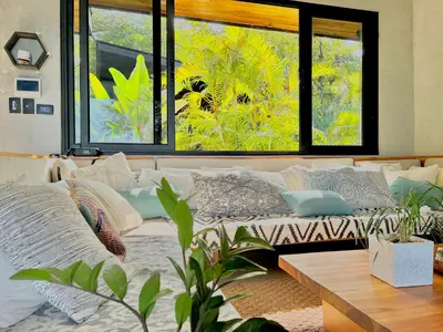 a living room with a couch and a large window at CASA BUHO and COZY JUNGLE CABANA in Santa Teresa Beach