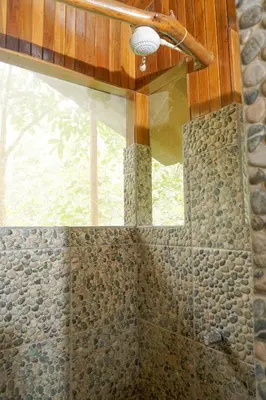 a bathroom with a shower with a stone wall at Tree Houses Hotel Costa Rica in Florencia