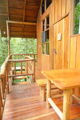 a porch of a cabin with a wooden table and bench at Tree Houses Hotel Costa Rica in Florencia