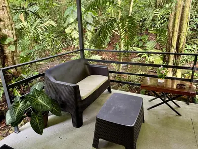 a balcony with a chair and a table and trees at The frog house in Fortuna