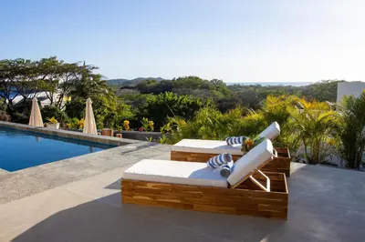 two lounge chairs sitting next to a swimming pool at Casa Ojos Azules, Nosara. New Listing in Nosara
