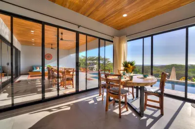 a dining room with glass walls and a table and chairs at Casa Ojos Azules, Nosara. New Listing in Nosara
