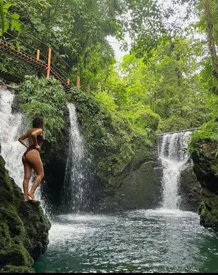 a woman in a bikini standing in front of a waterfall at Pozas y Cascadas La Presa Habitación 1 in Río Cuarto