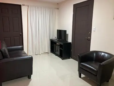a living room with two chairs and a television at Hospedaje Ana Lu 2, Only 10 minutes from airport in Alajuela City