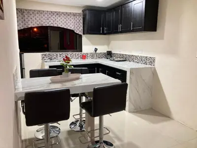 a kitchen with black cabinets and a table with chairs at Hospedaje Ana Lu 2, Only 10 minutes from airport in Alajuela City