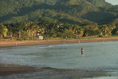 a person standing in the water at the beach at Modern 4BR Home, Pool, Parking, Walk To The Beach in Playa Flamingo