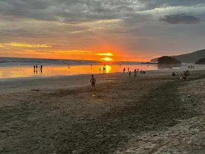 a group of people on a beach at sunset at Modern 4BR Home, Pool, Parking, Walk To The Beach in Playa Flamingo