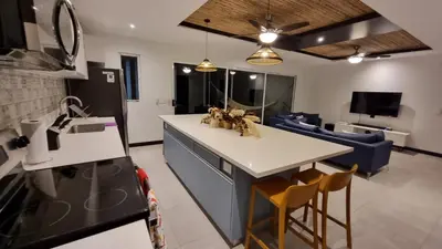 a kitchen and living room with a kitchen island and a couch at Casa Cardumen - Ciudad Del Mar, in Jaco in Jacó