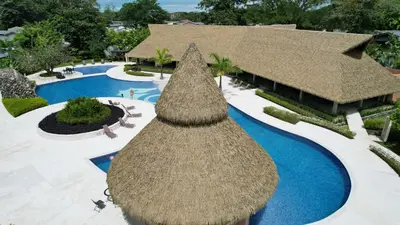 an overhead view of a resort swimming pool with a straw umbrella at Casa Cardumen - Ciudad Del Mar, in Jaco in Jacó