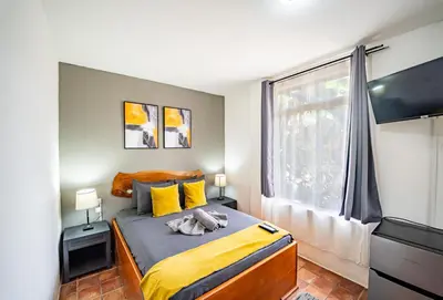a bedroom with a bed with yellow sheets and a window at La Flor de Coco in Sámara
