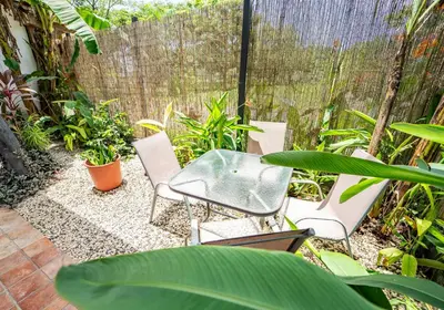 a patio with a table and chairs in a garden at La Flor de Coco in Sámara