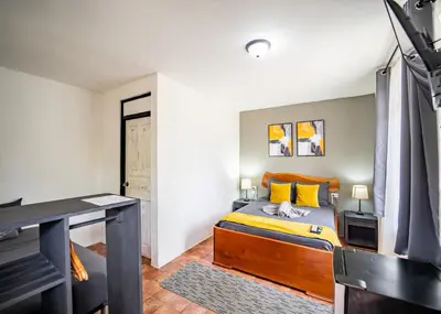 a bedroom with a bed with yellow pillows and a desk at La Flor de Coco in Sámara
