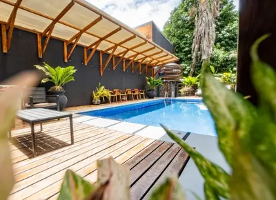 a patio with a pool and a wooden deck with a pergola at La Flor de Coco in Sámara