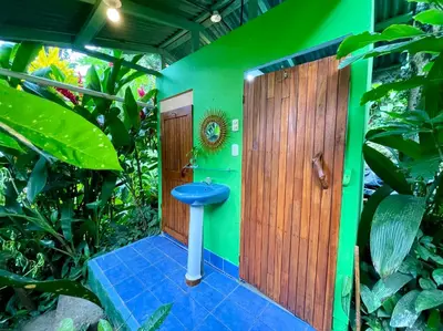 a bathroom with a blue toilet in a green wall at The Chorotega Hotel, Montezuma in Montezuma