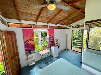 a room with a bed and a table and windows at The Chorotega Hotel, Montezuma in Montezuma