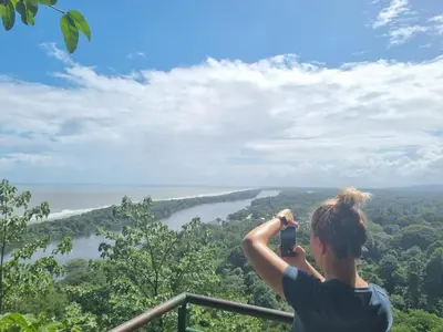 a woman taking a picture of a river with a camera at Micheck beach house in Tortuguero