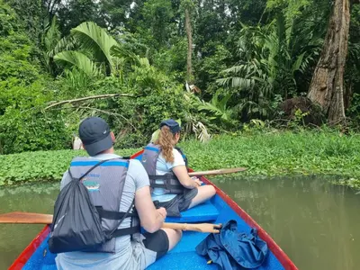 two people in a boat on a river at Micheck beach house in Tortuguero