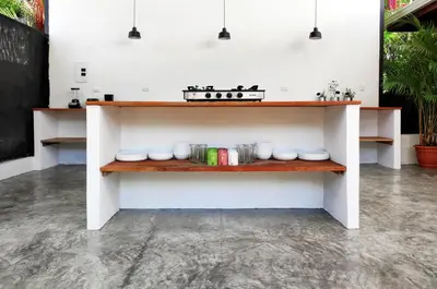 a kitchen with a shelf with dishes and a stove at ICO Living Hostel in Santa Teresa Beach